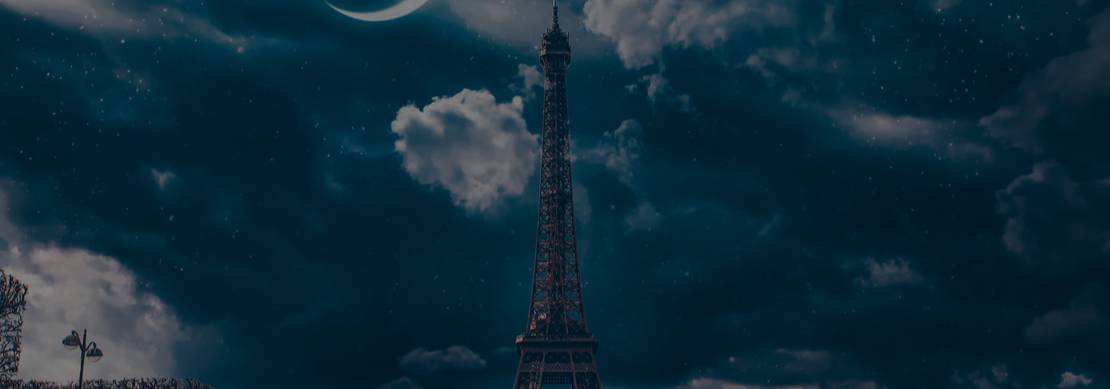 An image of the Eiffel tower in France at night against a dark blue crescent moonlit sky with clouds and stars