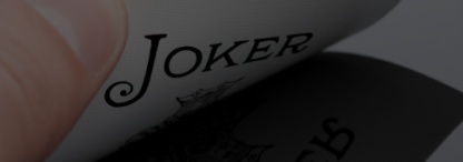 A close-up image of a male hand holding a joker card