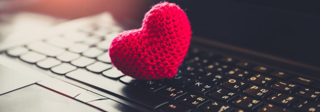 A closeup of a red knitted heart on a laptop keyboard