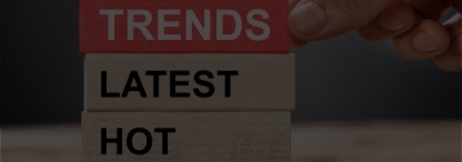 A close-up image of a hand stacking wooden blocks with the words trends, latest, hot and popular on a wooden table