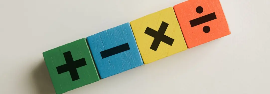 four brightly colored cubes with + - x ÷ printed on them