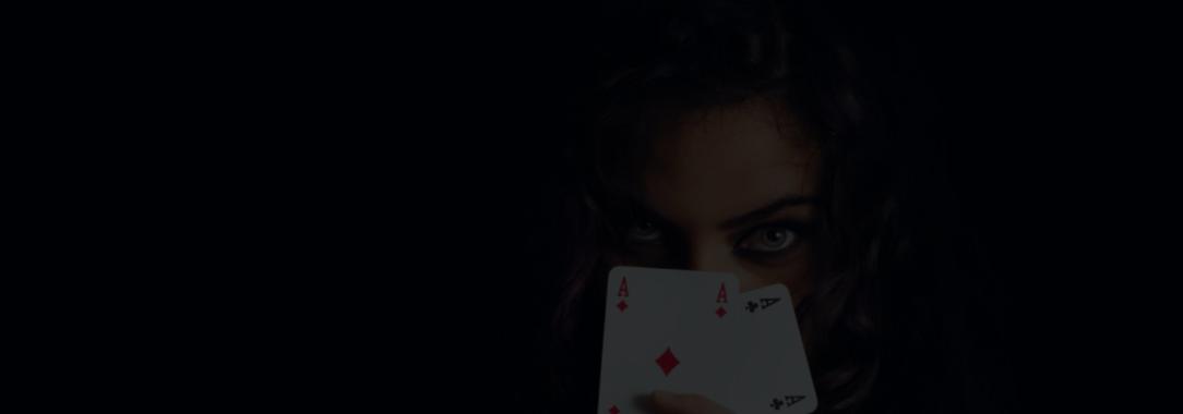 A photo of a woman hiding her face behind two aces playing Texas Hold Em on a tablet on a dark background