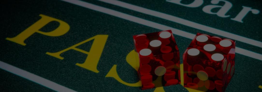A close-up photo of red dice with white pips sitting on the Pass Line section of the craps layout 