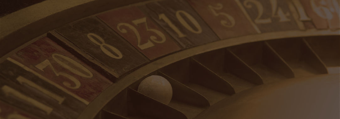 A closeup photograph of an antique wooden roulette wheel with the white ball in black slot number 8