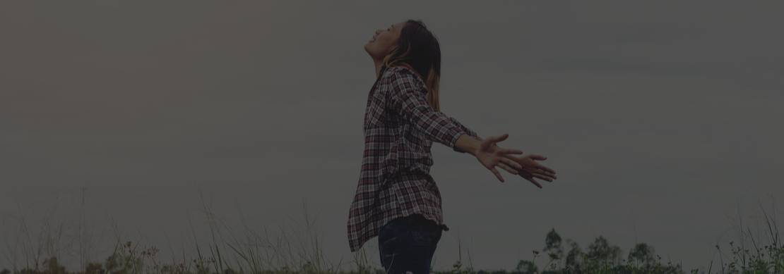 woman standing in the middle of a field - taking a deep breath